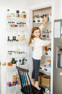Little girl climbing on chair and searching the pantry